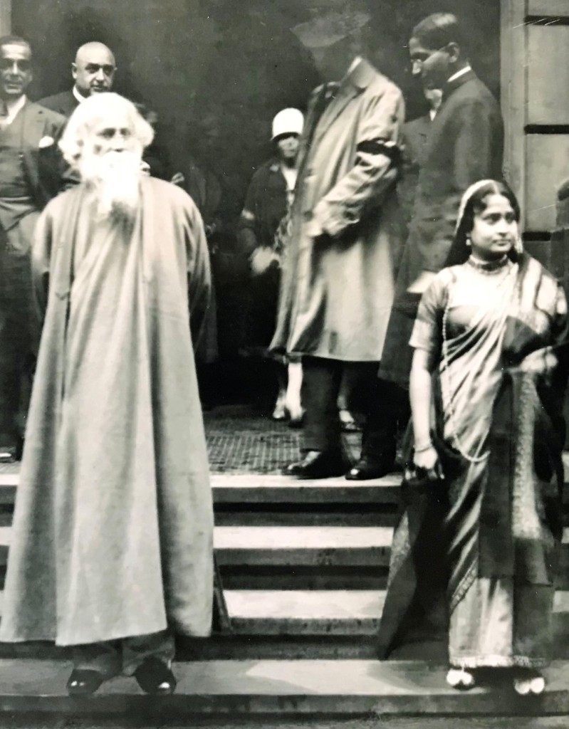 Rabindranath Tagore (links) bei seinem Besuch in Hamburg, 1926, auf einer Steintreppe mit Begleitung.